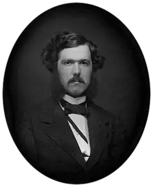 Black-and-white photograph of a young man with a mustache
