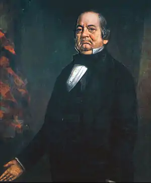 A short, balding man in a black suit